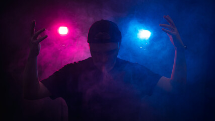 The silhouette of a man against the background of smoke, consecrated by red and blue light