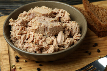 Board with plate of canned tuna on wooden background