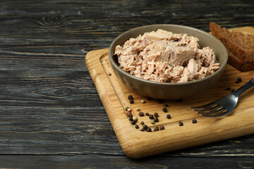 Board with plate of canned tuna on wooden background