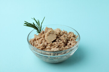 Glass bowl with canned tuna on blue background