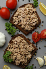 Sandwiches with canned tuna and ingredients on gray background