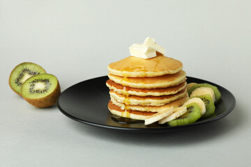 Plate with delicious pancakes and kiwi on gray background