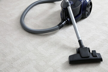 Modern vacuum cleaner on carpet indoors. Space for text