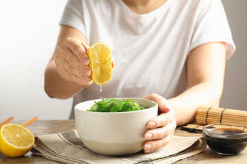 Woman eating Japanese seaweed salad at table, closeup © New Africa