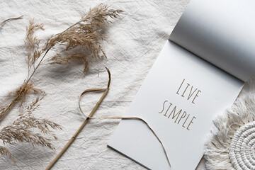 Text Live Simple in block note. Envelope, macrame and pampas grass.. Simple minimal flat lay on...
