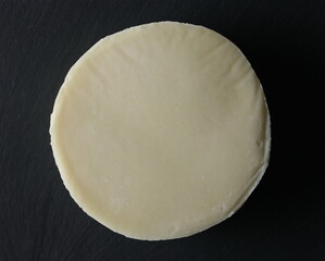Semi-hard round cheese isolated on black background with clipping path, top view