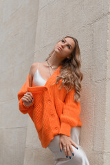 Portrait of fashionable women in orange sweater and beige sweater posing in the street