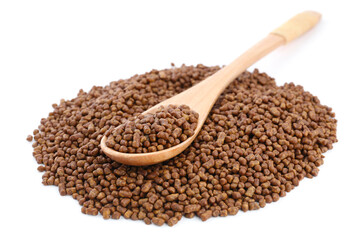 Wooden spoon and buckwheat tea granules on white background