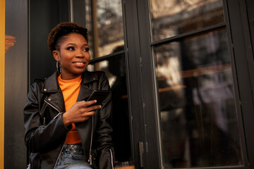 Young african woman using the phone. Beautiful woman drinking coffee.