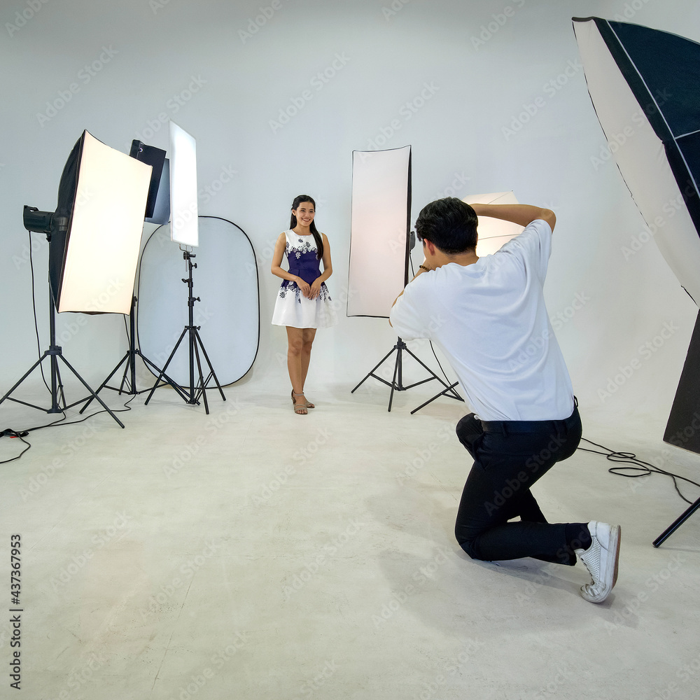 Wall mural an asian photographer is photographing a model posing in the studio.