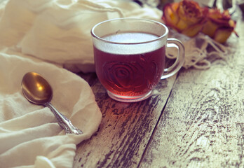 Cup of  tea, neutral scarf on wooden table, sun glare and bokeh, the concept of home comfort, retro atmosphere. Romantic morning