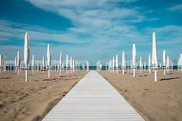 Fotobehang Riviera Romagnola spring view. Almost summer, clue skies, white walking path, sunbeds and umbrellas ready for season opening. Italian vintage riviera beach on the adriatic coast.  © laura