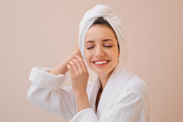 Beautiful young woman with hair wrapped in towel after washing on beige background