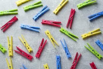 Colorful plastic clothespins on grey table, flat lay