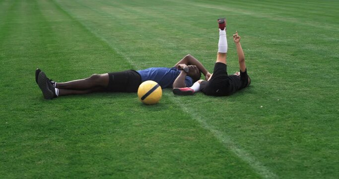 Diverse father and son playing on football pitch during break