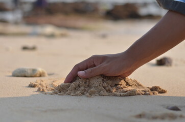 cropped male hand playing sand and relaxing on the beach with beach background blur