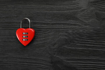 Red heart shaped combination lock on black wooden table, top view. Space for text