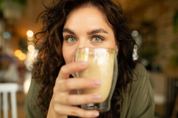 close up portrait funny happy face of young pretty woman with curly hair drinking and enjoying coffee in coffee shop