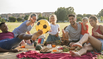 Happy multiracial families doing picnic outdoor in city park during summer vacation - Main focus on...