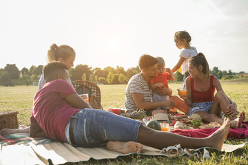 Happy multiracial families doing picnic outdoor in city park during summer time - Main focus on...