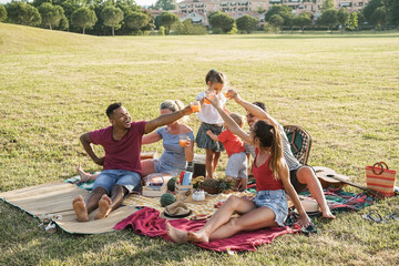 Happy multiracial families doing picnic outdoor in city park during summer - Main focus on african...