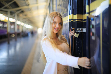 young woman waiting in vintage train, relaxed and carefree at the station platform in Bangkok, Thailand before catching a train. Travel photography. Lifestyle.