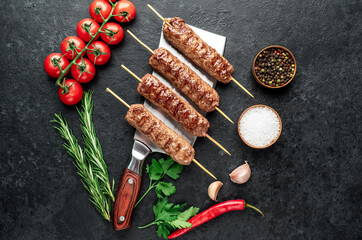 grilled Lula kebab on skewers with spices on the knife on a stone background