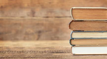 Back to school and education concept. The stack of books on the wooden background and place for text.
