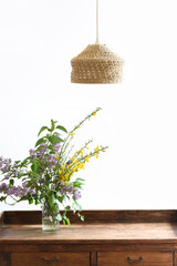 Minimalist interior decoration with lamp, wooden furniture and wildflowers