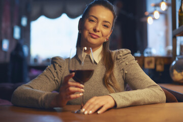 Hand of a young beautiful woman holding a glass of wine indoors of a stylish wine restaurant