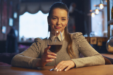 Hand of a young beautiful woman holding a glass of wine indoors of a stylish wine restaurant