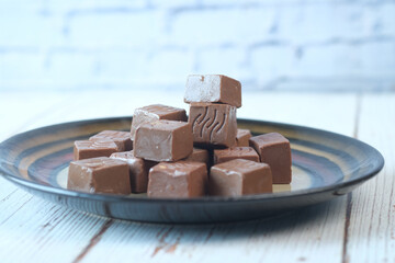 Pieces of dark chocolate on plate .