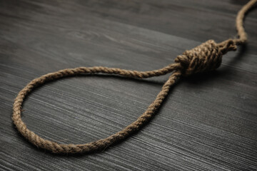 Rope noose on black wooden table, closeup
