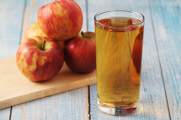 A glass with apple juice and ripe apples