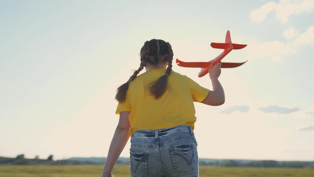 Happy kid in park. Girl run with toy airplane. Sunset in the park. Kid dream. Happy kid run with toy airplane. Happy childhood concept. Girl run pilot of plane. Kid pilot in park. Girl dream at sunset