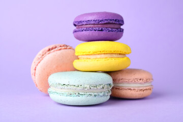 Pile of delicious colorful macarons on violet background, closeup