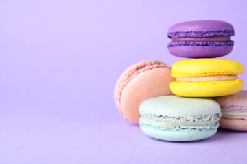 Obraz na płótnie Canvas Delicious colorful macarons on violet background. Space for text