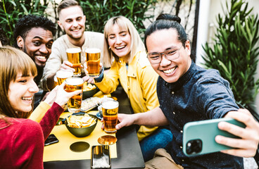 Happy multiracial friends drinking beer at brewery pub - Young people having fun taking a selfie at bar restaurant - Friendship concept