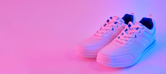 Fashion white sneakers in neon light. Sport shoes for training in the gym. Creative minimalism. 90s concept.
