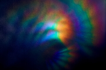 Blurred Bright multicolored glare on dark rough textured cardboard. Soft rainbow light. Abstract...