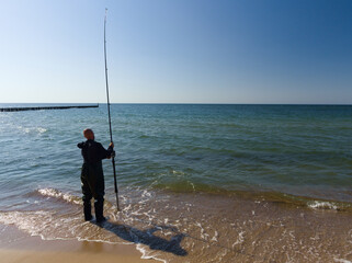 Wędkarz łowiący ryby z plaży - obrazy, fototapety, plakaty
