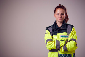 Studio Portrait Of Serious Young Female Paramedic Against Plain Background