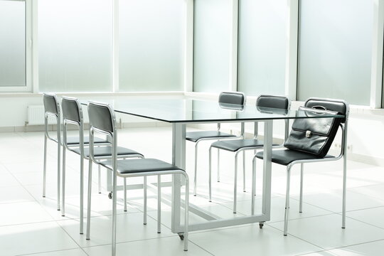 Glass table chairs and briefcase in office space
