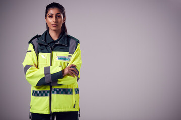 Studio Portrait Of Serious Young Female Paramedic Against Plain Background