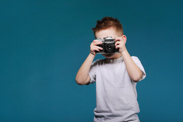 Little boy taking a picture using a retro camera. Child boy with vintage photo camera isolated on...