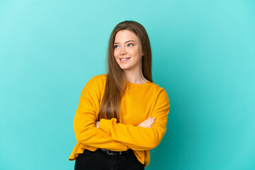 Obraz premium Teenager girl over isolated blue background looking up while smiling