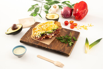 Venezuelan arepa with bacon, avocado, lots of grated cheese, parsley and vegetables