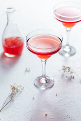 Cosmopolitan cocktail served with lemon wedges on a white background