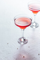 Cosmopolitan cocktail served with lemon wedges on a white background