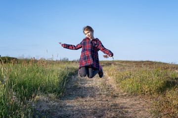 Happy little girl jumping and enjoying life on a spring path along picturesque coastline